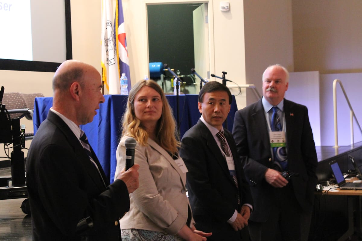 Four panellists seated at a table on a stage, answering a question put to them from the floor at the end of a conference session